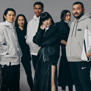 A group of six people dressed in casual sporty clothing pose confidently against a simple grey background, displaying fashion styles featuring monochromatic colors and sporty hoodies and jackets